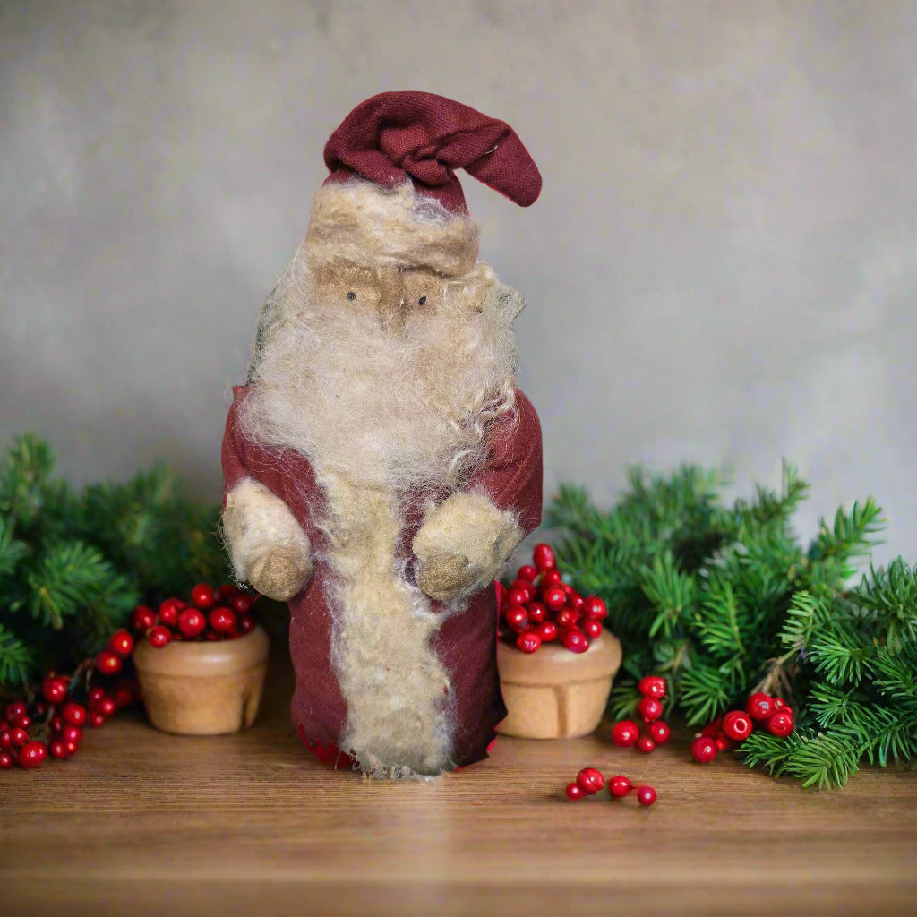 Stuffed fabric Santa in red coat among greenery