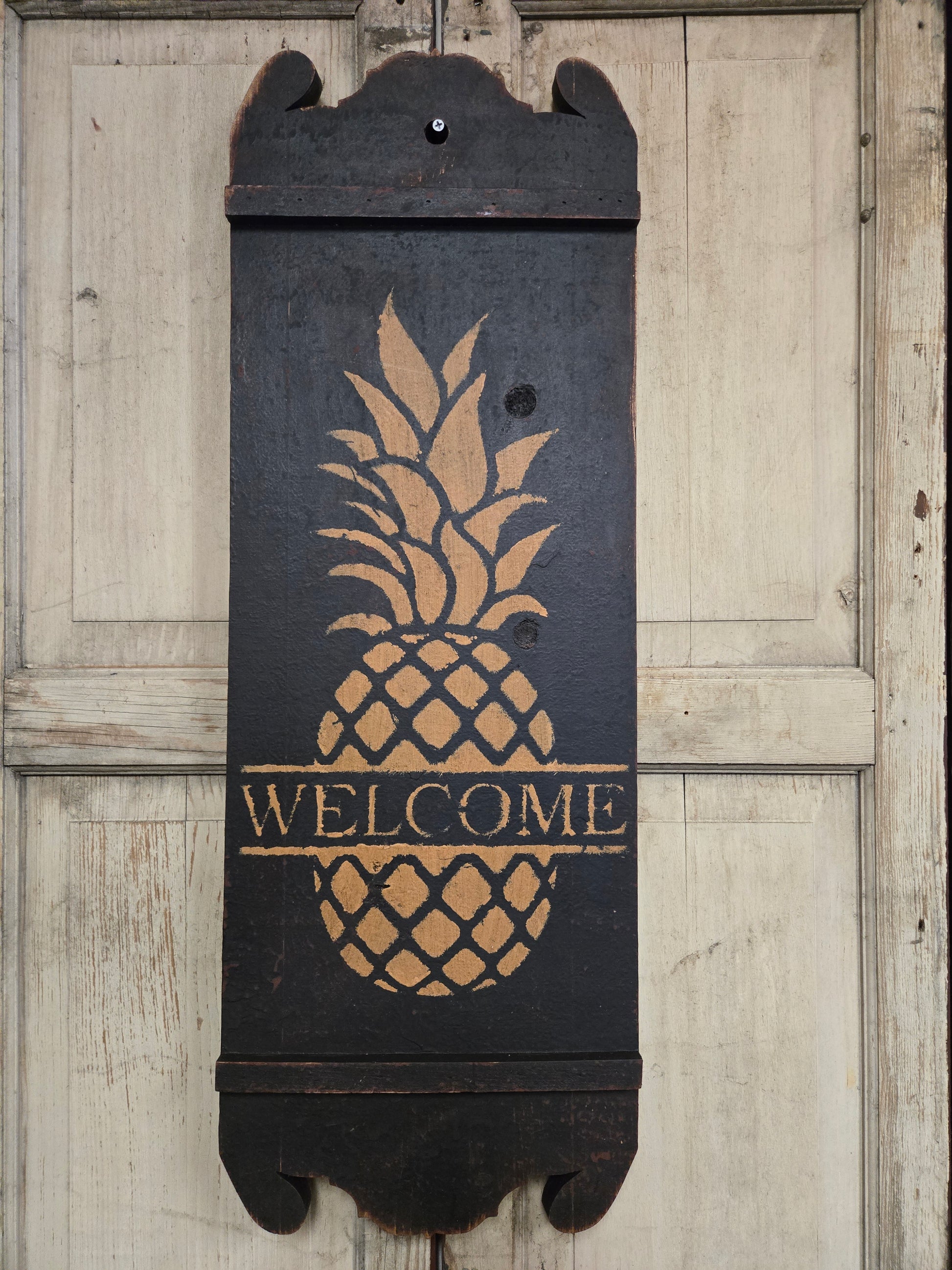 Sign with pineapple design and 'Welcome' text on a wooden floor