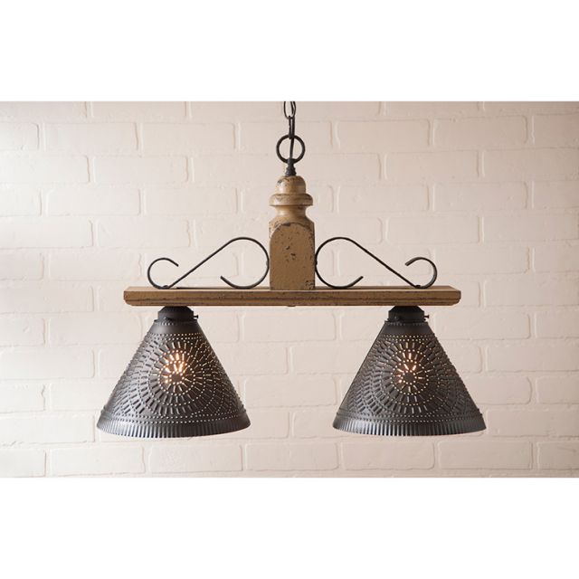 Wooden pendant light fixture with metal shades against a white brick wall.