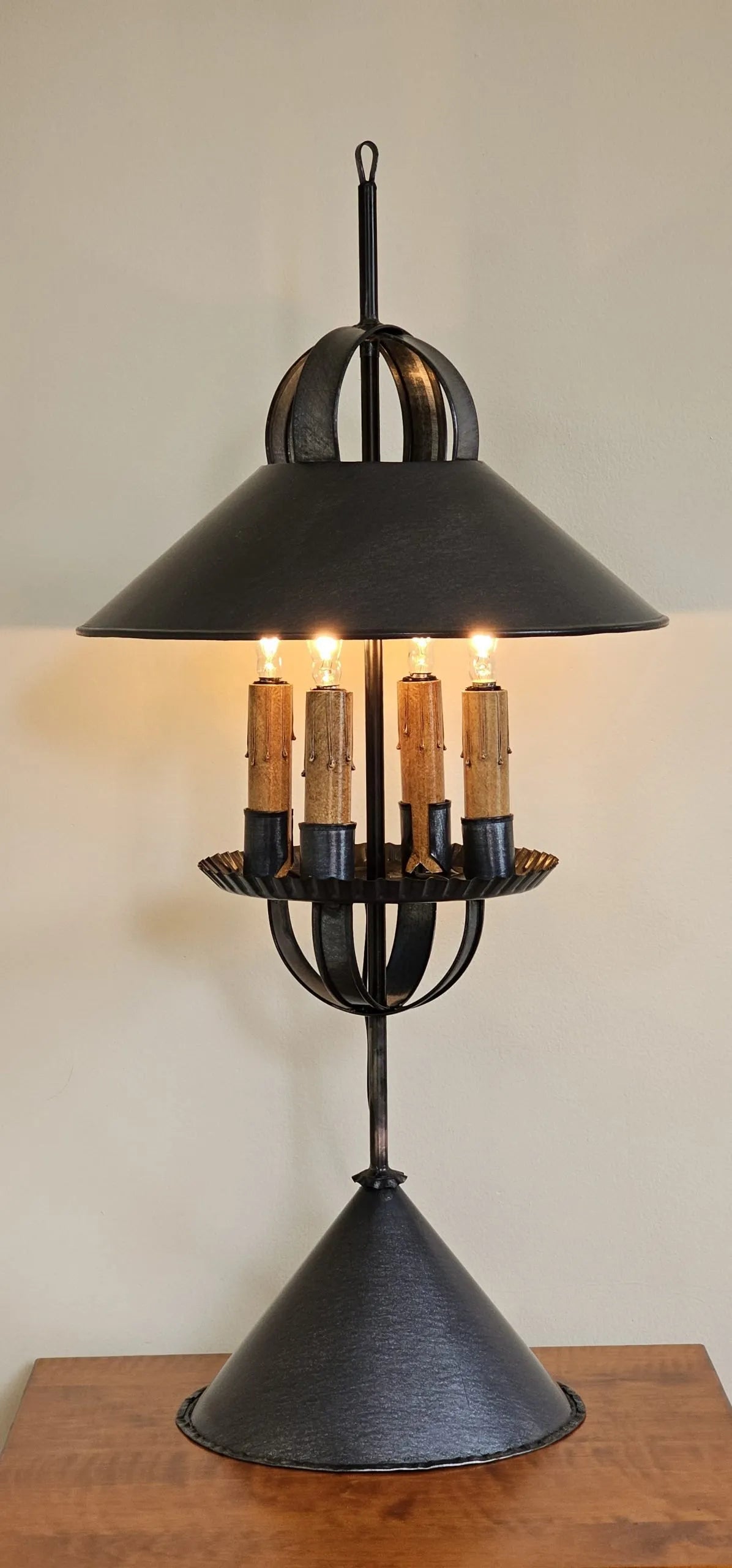 Decorative black metal lamp with multiple candle-like lights on a wooden surface.