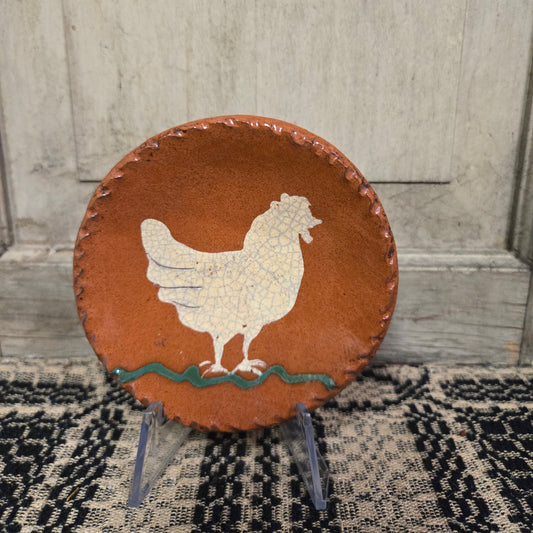 Small round redware plate with a white chicken and a green squiggly line