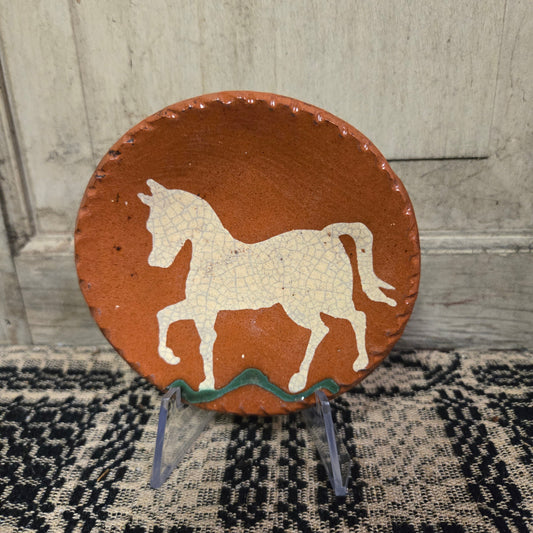 Small round redware plate with a white horse prancing on green grass