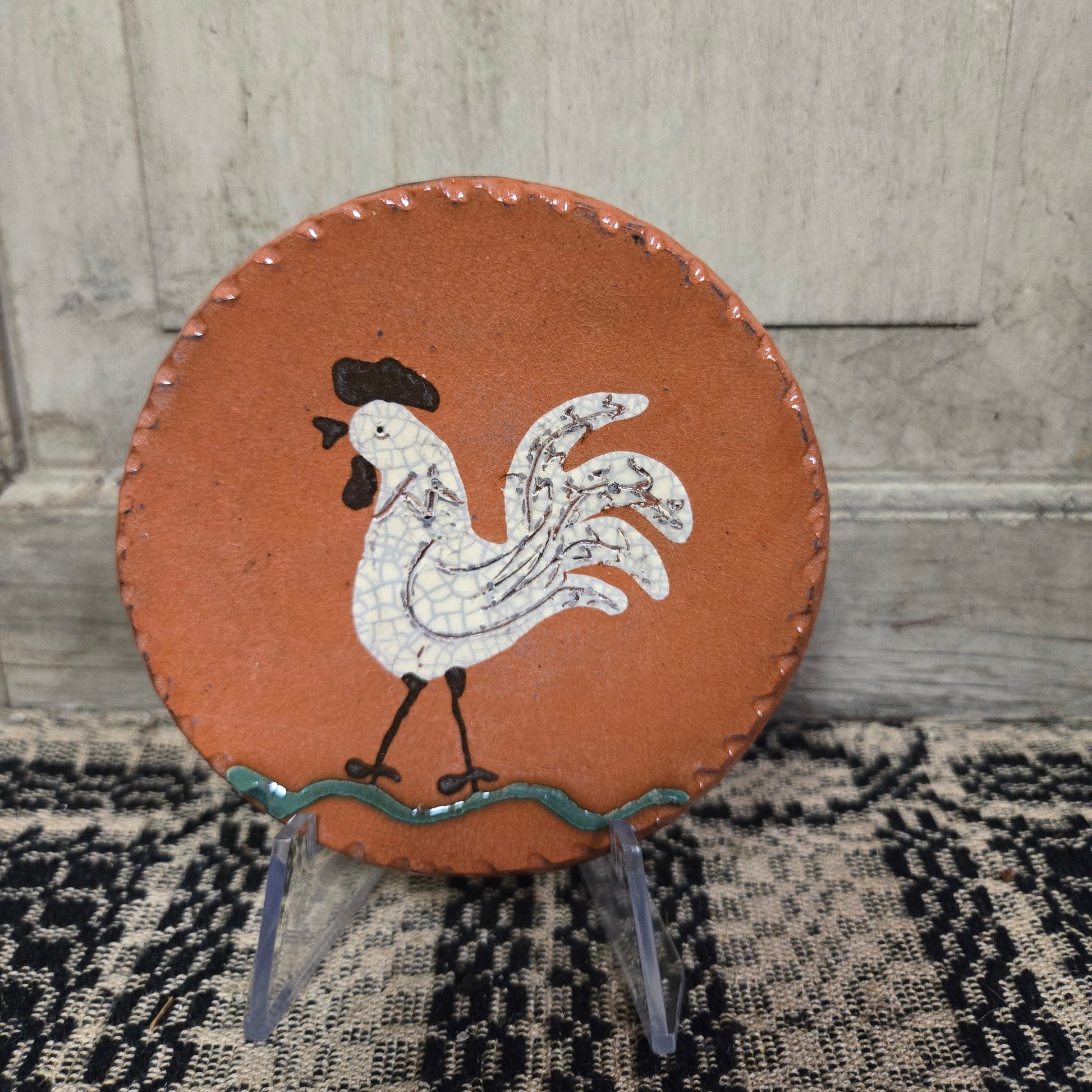 Small round redware plate with white rooster in a vibrant cream color glaze