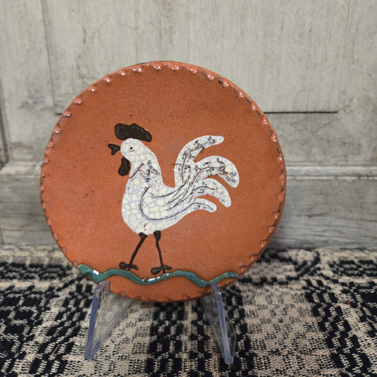 Small round redware plate with white rooster in a vibrant cream color glaze