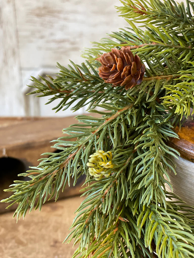 Close-up of green pine branches with pinecones on a wooden surface