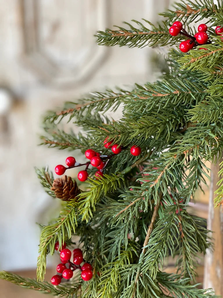 Green Christmas garland with red berries and pinecones on a blurred background