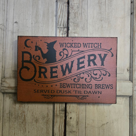 Wooden sign with 'Wicked Witch Brewery' design on a wooden background