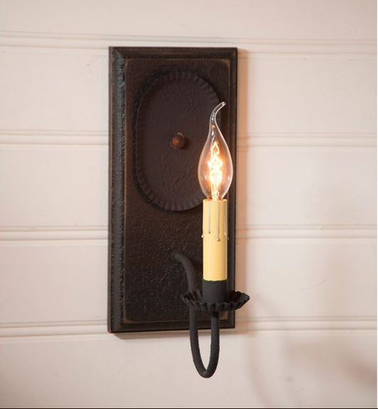Decorative wall sconce with a lit bulb on a neutral wall background
