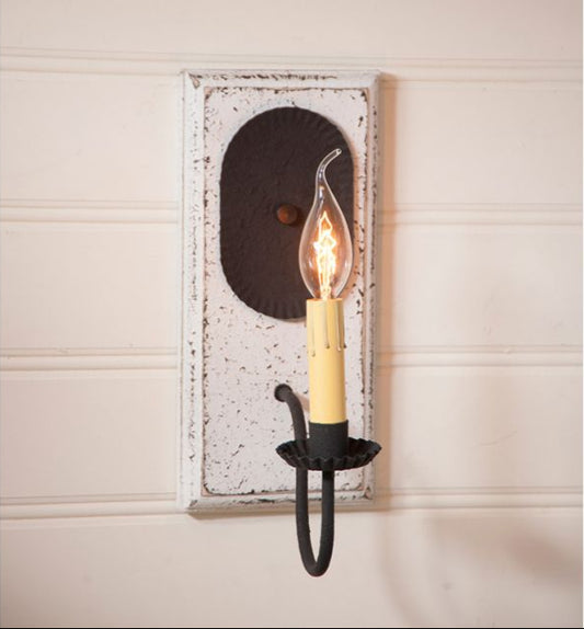 Wall-mounted candle holder with a light bulb inside on a beige wall.