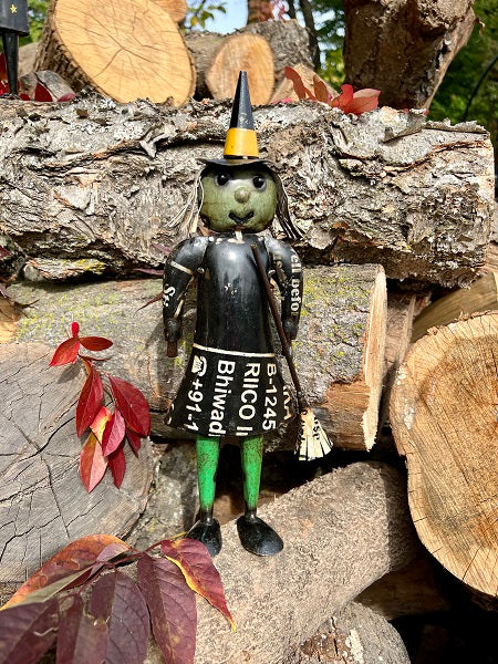 Scarecrow figurine with a witch hat on a wooden log pile