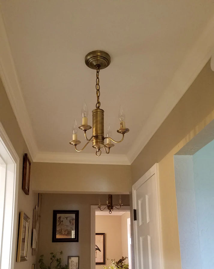 Four arm chandelier in a hallway surrounded by art.