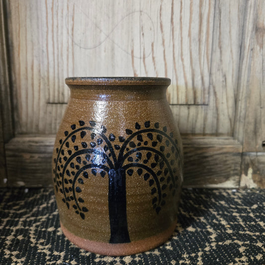 Brown ceramic vase with black tree design on a woven surface