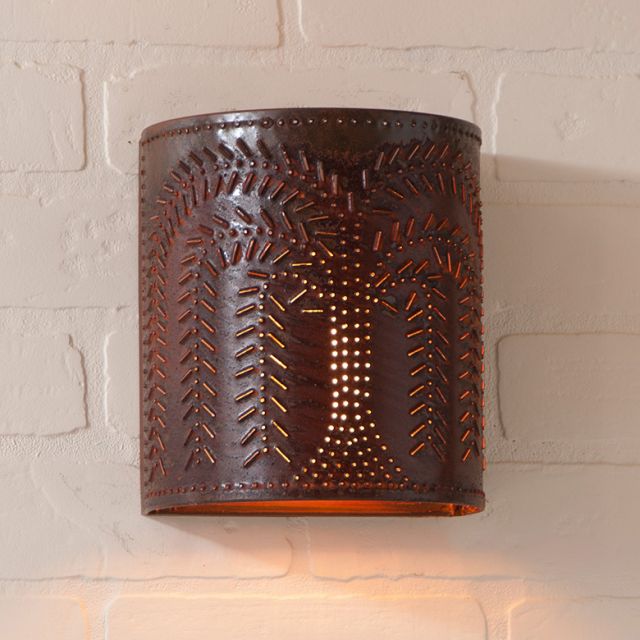 Decorative wall sconce with embossed design on a light brick wall.