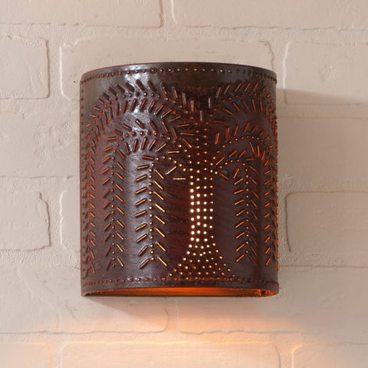 Decorative wall sconce with embossed design on a light brick wall.