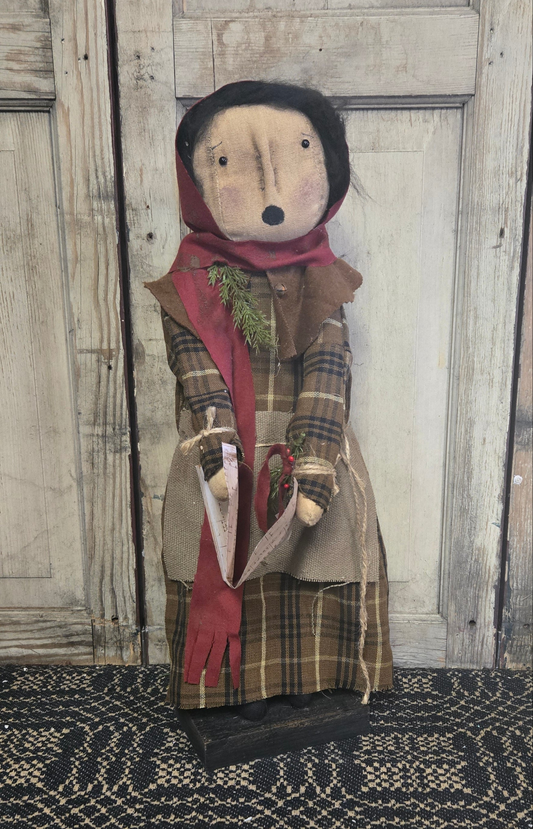 A festive holiday figurine of a female character in a red and brown checkered dress, holding a song book, with a wooden backdrop.
