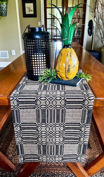 Decorative pineapple on a table with a black and white patterned runner