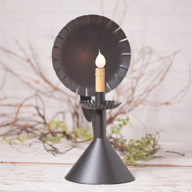 Black decorative candle holder with a lit candle on a light background