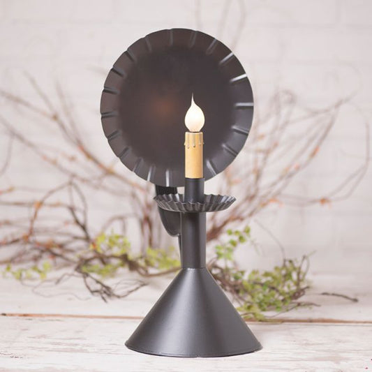 Black decorative candle holder with a lit candle on a light background
