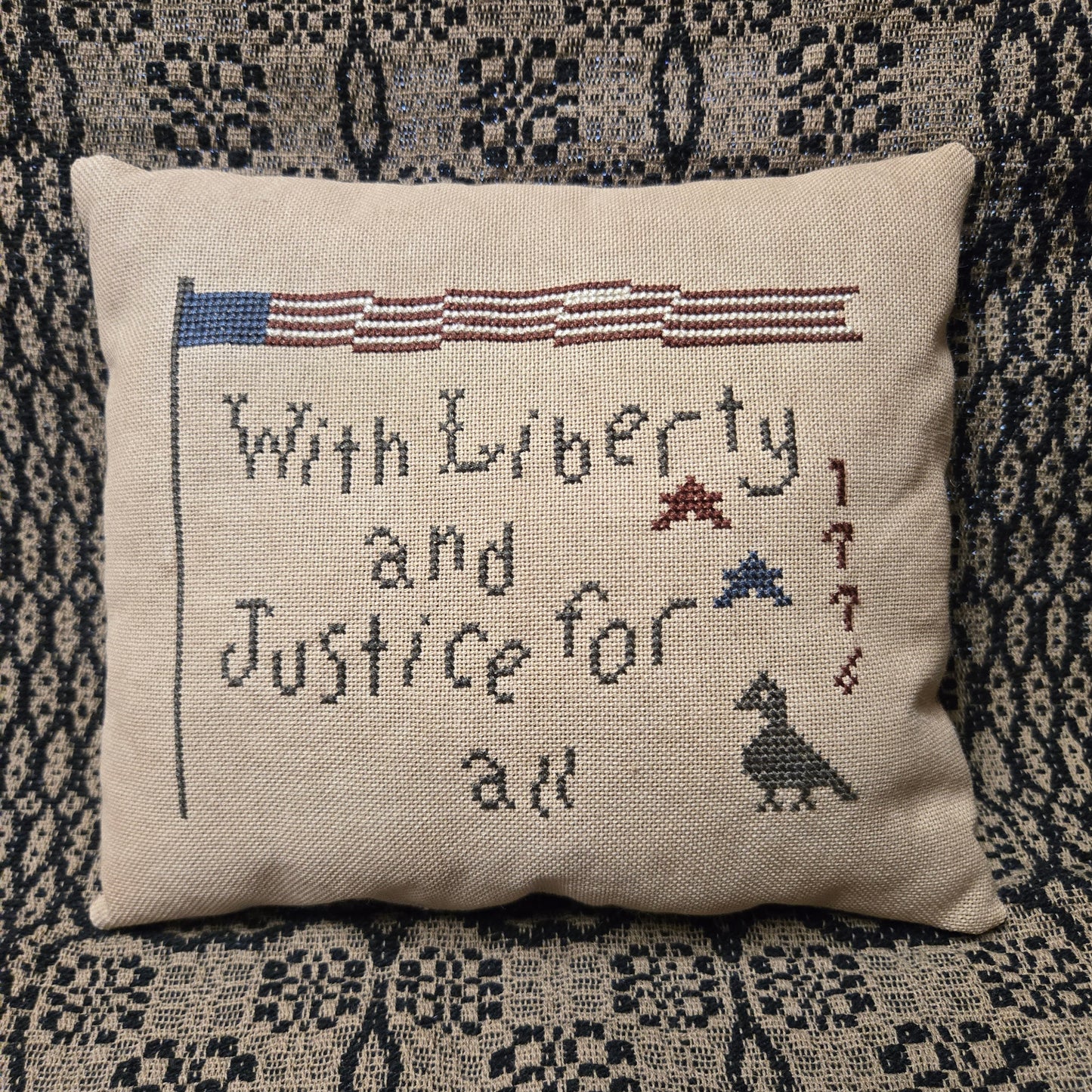 Decorative pillow with embroidered text and symbols on a textured fabric background