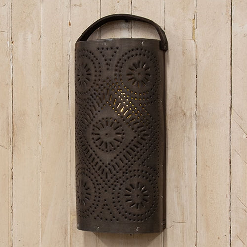Decorative metal wall lantern with intricate patterns on a wooden wall.