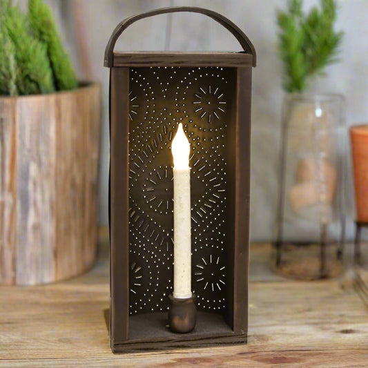Decorative wall lantern with a lit candle inside on a blurred background with greenery