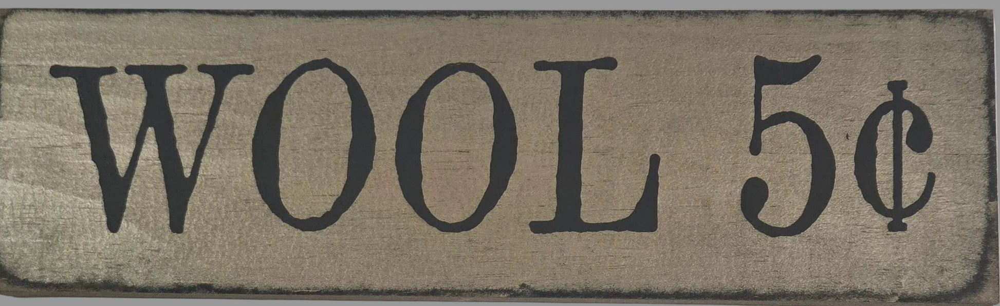 Wooden sign with 'WOOL 5c' text on a gray background