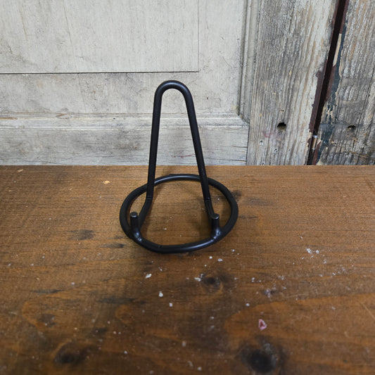 A wrought iron mini standing plate holder, black in color, placed on a wooden surface.