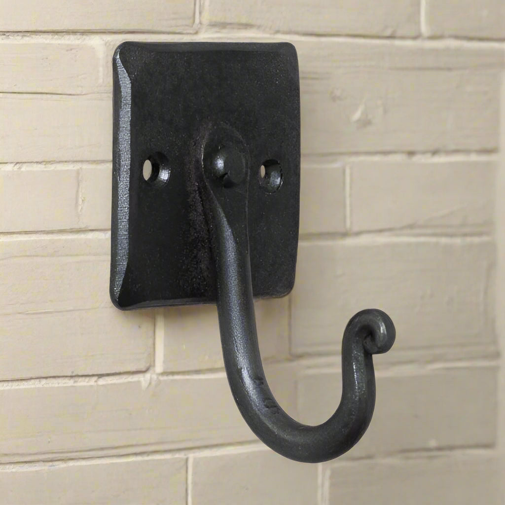 A black wrought iron wall hook with a mount plate, featuring a rustic finish and a small backplate mount.