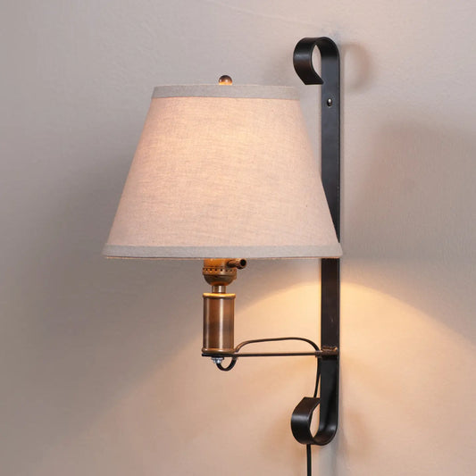 Wall-mounted lamp with a white shade and black metal fixture on a gray wall.