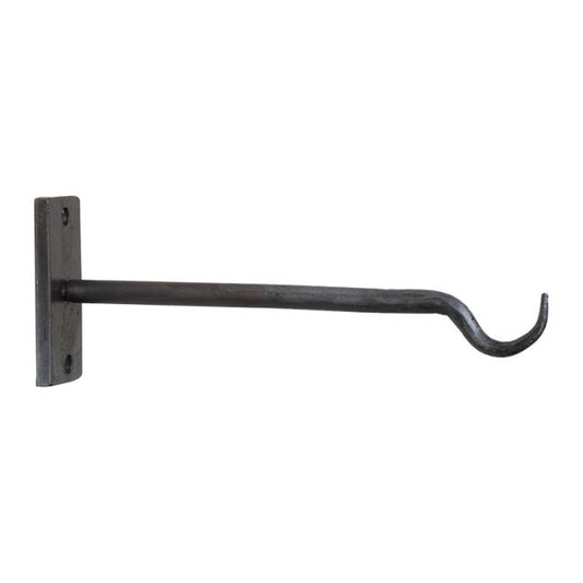 A wrought iron wall mounted plant hanger with an antique finish, featuring a curved hook and a horizontal bar, mounted on a plain wall.