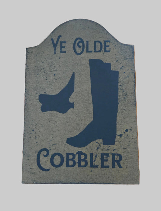 Decorative sign with boot silhouette and 'Ye Olde Cobbler' text on a wooden background
