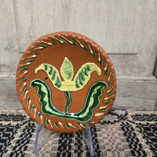 Small round redware plate with a vibrant yellow tulip and an intricate border