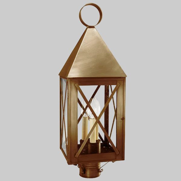 Decorative outdoor lantern with brass finish on a gray background