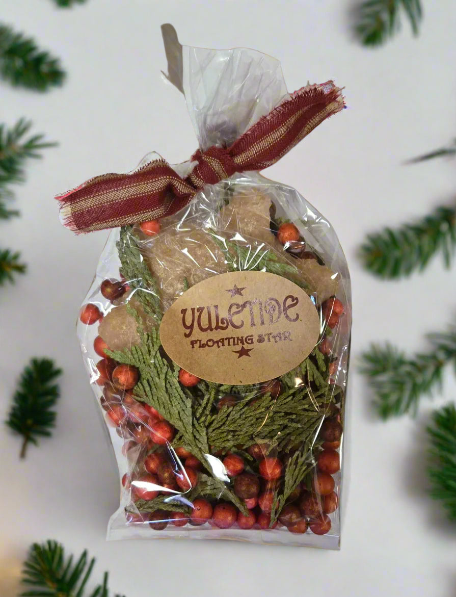 A packaged Yuletide floating candle kit with red berries and green foliage, tied with a ribbon.
