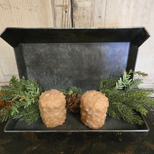Decorative tray with two beige spherical objects and greenery on a wooden surface